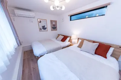 two beds in a room with white walls and a window at Birthday House Komagome in Tokyo