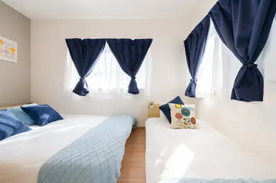 two beds in a bedroom with blue curtains at 70sqm Private House, Major Tokyo Spots & Free Parking in Tokyo