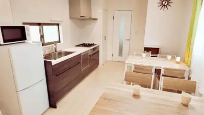a kitchen with a white refrigerator and a table at MSTAY\u9ad8\u7530\u99ac\u5834one in Tokyo