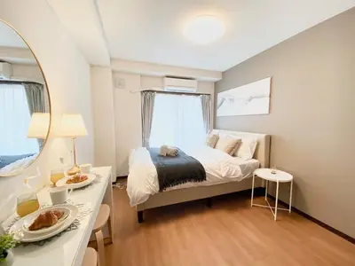 a bedroom with a bed and a table and a mirror at OHANAJAYAsquare302 in Tokyo
