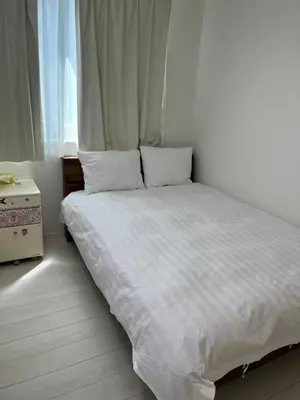 a bedroom with a bed with white sheets and a window at Tokyo Link House Halona-Direct to Shinjuku, Shibuya, Ginza in Tokyo