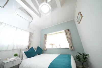 a bedroom with a white bed and blue pillows at \u5927\u4eba\u6c17\u30a8\u30ea\u30a2\u65b0\u5bbf\u307e\u3067\u96fb\u8eca4\u5206 Jr\u6771\u4e2d\u91ce\u99c5\u5f92\u6b696\u5206 \u5927\u4e45\u4fdd\u99c5\u5f92\u6b6910\u5206 \u6700\u59275\u540d\u69d8 \u304a\u8377\u7269\u9810\u53ef in Tokyo