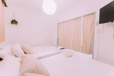 two beds in a white room with a tv at Showa Bloom Stay Near Shinjuku & Yoyogi in Tokyo