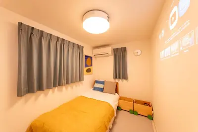 a bedroom with a bed with a yellow blanket at \u6771\u5411\u5cf6House in Tokyo