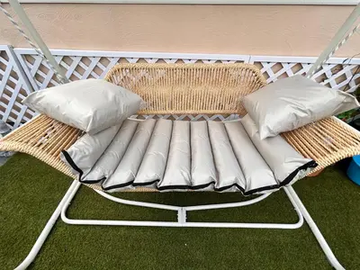 a wicker chair with two pillows on a porch at MOMO Garden in Tokyo