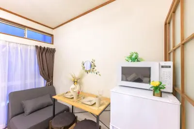 a small living room with a couch and a microwave at \u65b0\u5bbf\u99c54\u52062\u99c5\u304b\u3089\u5f92\u6b6910\u5206 \u6700\u59273\u540d \u9ad8\u901fWiFi 1\u968e\u306e\u307e\u308b\u307e\u308b\u8cb8\u5207\u90e8\u5c4b in Tokyo