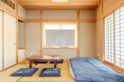 a room with a bed and a table and windows at Kizen Villa in Tokyo