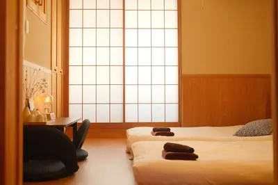 a room with two beds and a desk and a window at SAYO Serene Traditional Home, 8-min walk to JR Yamanote Line in Tokyo