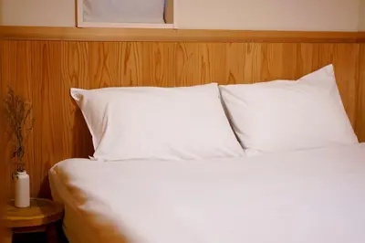 a bed with white pillows and a candle on a table at SAYO Serene Traditional Home, 8-min walk to JR Yamanote Line in Tokyo