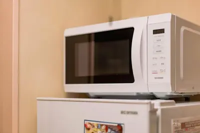 a microwave sitting on top of a refrigerator at SAYO Serene Traditional Home, 8-min walk to JR Yamanote Line in Tokyo