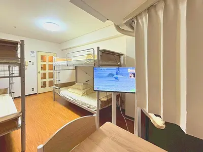 a room with two bunk beds and a flat screen tv at Shibuya Lions in Tokyo