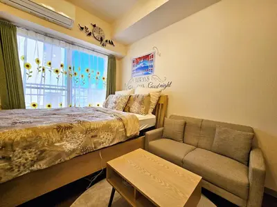 a bedroom with a bed and a couch and a window at Cozy room Airport and Disneyland direct bus in Tokyo