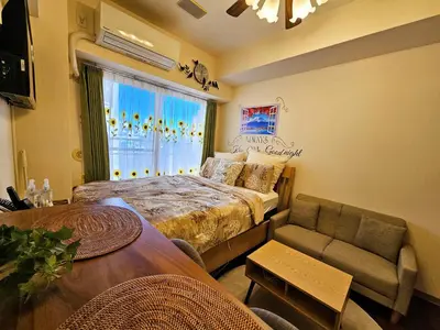 a bedroom with a bed and a table and a window at Cozy room Airport and Disneyland direct bus in Tokyo