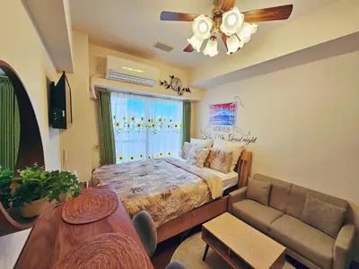 a bedroom with a bed and a couch and a window at Cozy room Airport and Disneyland direct bus in Tokyo