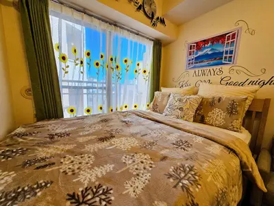 a bedroom with a bed and a window with sunflowers at Cozy room Airport and Disneyland direct bus in Tokyo