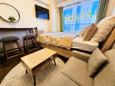 a bedroom with a bed and a couch and a window at Cozy room Airport and Disneyland direct bus in Tokyo