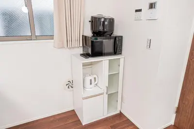 a microwave sitting on top of a stand in a room at \u6625\u660eHouse in Tokyo