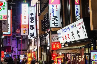 a busy city street at night with signs at IKEPOND HOUSE Tokyo in Tokyo