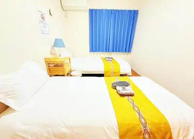 a bedroom with two beds with a yellow and white blanket at \u6c60\u888b\u672c\u753a102 in Tokyo