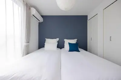 a bedroom with two beds and a blue wall at \u56db\u5b63\u306e\u5bbf \u65b0\u7bc9\u4e00\u8ed2\u5bb6\u8cb8\u5207 \u65d7\u30f6\u8c37\u99c5\u5f92\u6b699\u5206 \u65b0\u5bbf4\u5206 \u9759\u304b\u3067\u4fbf\u5229\u306a\u4f4f\u5b85\u8857 \u6700\u59276\u540d in Tokyo