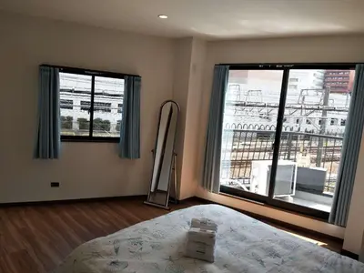 a bedroom with a bed and two large windows at \u611b\u306e\u5c4b\u6c11\u6cca\u6c60\u888b in Tokyo