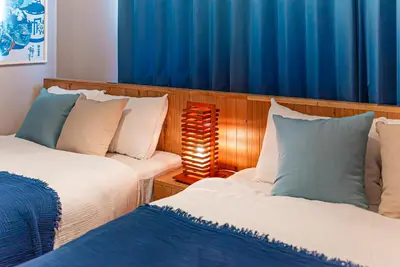 a bedroom with two beds and a blue curtain at Third Place Tokyo - Aoto - in Tokyo