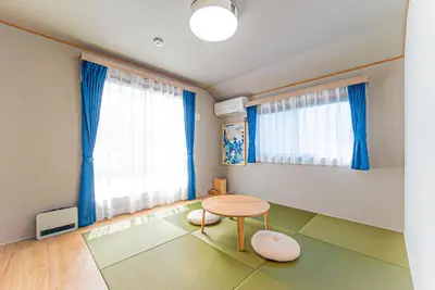 a living room with a table and blue curtains at Third Place Tokyo - Aoto - in Tokyo