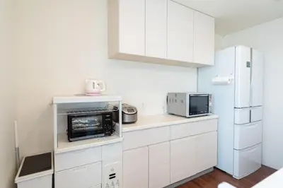 a white kitchen with white cabinets and a microwave at Omorikita 4chome House in Tokyo