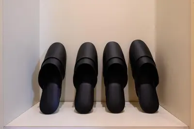 a row of black shoes sitting on a shelf at 6min Shibuya Station 4 Max A165 in Tokyo