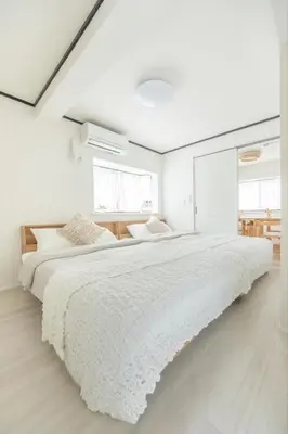 a white bedroom with a large bed with white sheets at Sunny Home Asakusa in Tokyo