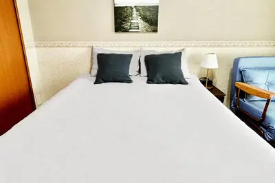 a large white bed with two pillows and a blue chair at \u65b0\u5bbf\u6b4c\u821e\u4f0e\u753a\u3059\u3050\u306e\u30ca\u30a4\u30c8\u30e9\u30a4\u30d5\u306b\u6700\u9069\u306aWi-Fi\u5b8c\u5099\u8cb8\u5207\u30a2\u30d1\u30fc\u30c8 in Tokyo