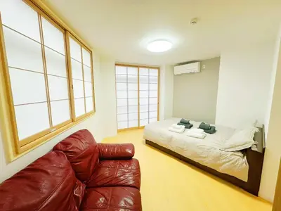 a bedroom with a bed and a leather couch at \u6587\u4eac\u30cf\u30a6\u30b9301 in Tokyo