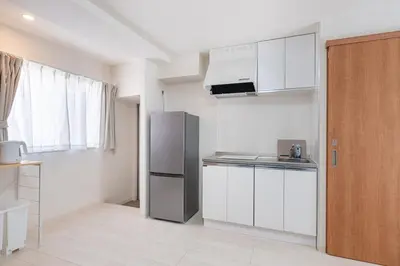 a kitchen with white cabinets and a stainless steel refrigerator at -Park Higashiueno- 4-minute walk from Ueno Station in Tokyo