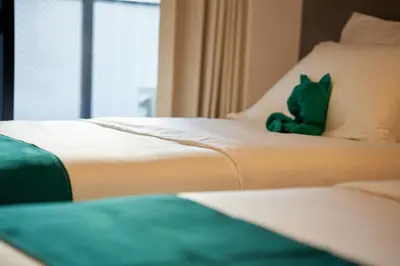 a green teddy bear sitting on top of a bed at livecasa\u8535\u524d brand-new hotel, a 3-minute walk from Asakusa Kuramae Statio in Tokyo