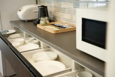 a kitchen with white dishes and a counter with a appliance at livecasa\u8535\u524d brand-new hotel, a 3-minute walk from Asakusa Kuramae Statio in Tokyo