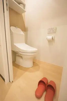 a bathroom with a toilet and a pair of red slippers at \u8aa0\u5bb6 Makoto Hotel in Tokyo