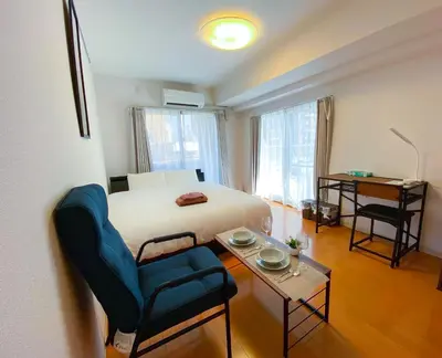 a bedroom with a bed and a chair and a table at Walk to JR Shinjuku - Grand Écru II 605 - Balcony & Kitchen in Tokyo