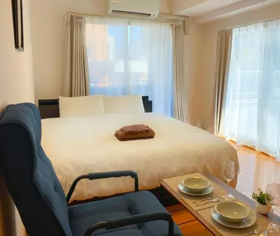 a bedroom with a bed and a chair and a table at Walk to JR Shinjuku - Grand Écru II 605 - Balcony & Kitchen in Tokyo