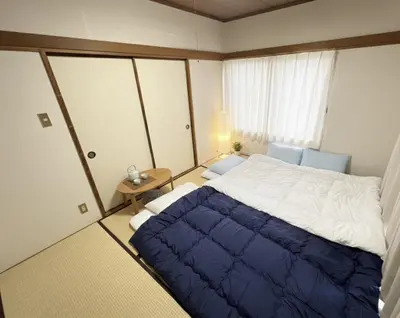 a bedroom with a large bed with a blue blanket at RHK Guest House102 in Tokyo