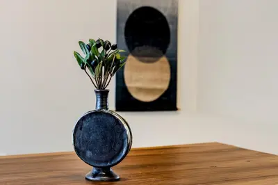 a black vase with flowers in it on a table at \u3059\u307f\u308c\u306e\u5bbf in Tokyo