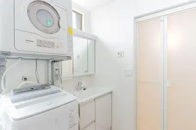 a white bathroom with a washing machine and a sink at Shibuya House in Tokyo