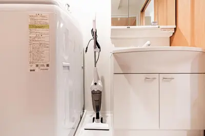 a white refrigerator in a kitchen with a vase on the floor at SAIEI HOTEl \u65b0\u5bbf in Tokyo