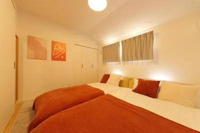 a bedroom with a large bed with an orange blanket at Zen Luxe in Tokyo