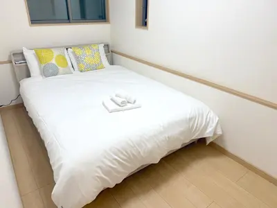 a white bed with a white towel on top of it at 池袋銀婚屋 GINKOU's HOUSE -- 2 min train to Ikebukuro Sunshine City in Tokyo