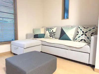 a living room with a couch and a ottoman at 池袋銀婚屋 GINKOU's HOUSE -- 2 min train to Ikebukuro Sunshine City in Tokyo