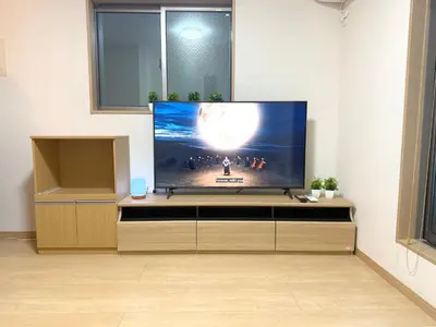 a flat screen tv sitting on top of a wooden entertainment center at 池袋銀婚屋 GINKOU's HOUSE -- 2 min train to Ikebukuro Sunshine City in Tokyo
