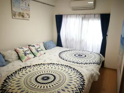 a bedroom with a bed with a white comforter and a window at \u611b\u306e\u5c4b\u6c11\u6cca\u65b0\u5bbf in Tokyo