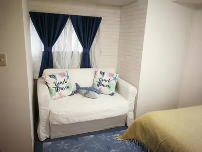 a white couch with two pillows on it in a bedroom at \u611b\u306e\u5c4b\u6c11\u6cca\u65b0\u5bbf in Tokyo