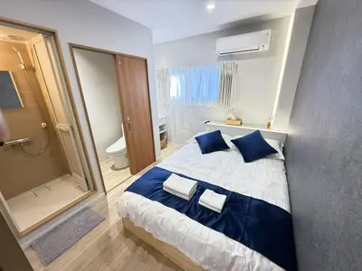 a bedroom with a bed with blue pillows and a shower at \u6d45\u8349\u99c5\u5f92\u6b698\u5206 \u6d45\u8349\u5bfa\u3059\u3050\u305d\u3070\u306e\u4ef2\u898b\u4e16\u6563\u7b56\u30b9\u30c6\u30a4 DqcYoE in Tokyo