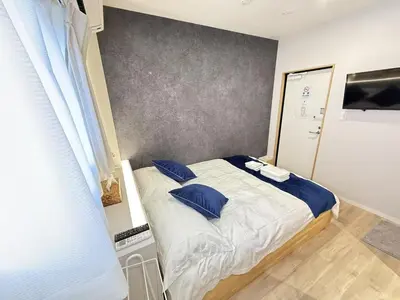 a small bedroom with a bed with blue pillows at \u6d45\u8349\u99c5\u5f92\u6b698\u5206 \u6d45\u8349\u5bfa\u3059\u3050\u305d\u3070\u306e\u4ef2\u898b\u4e16\u6563\u7b56\u30b9\u30c6\u30a4 DqcYoE in Tokyo